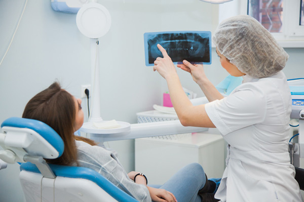Woman in dental chair looking at xray with dentist